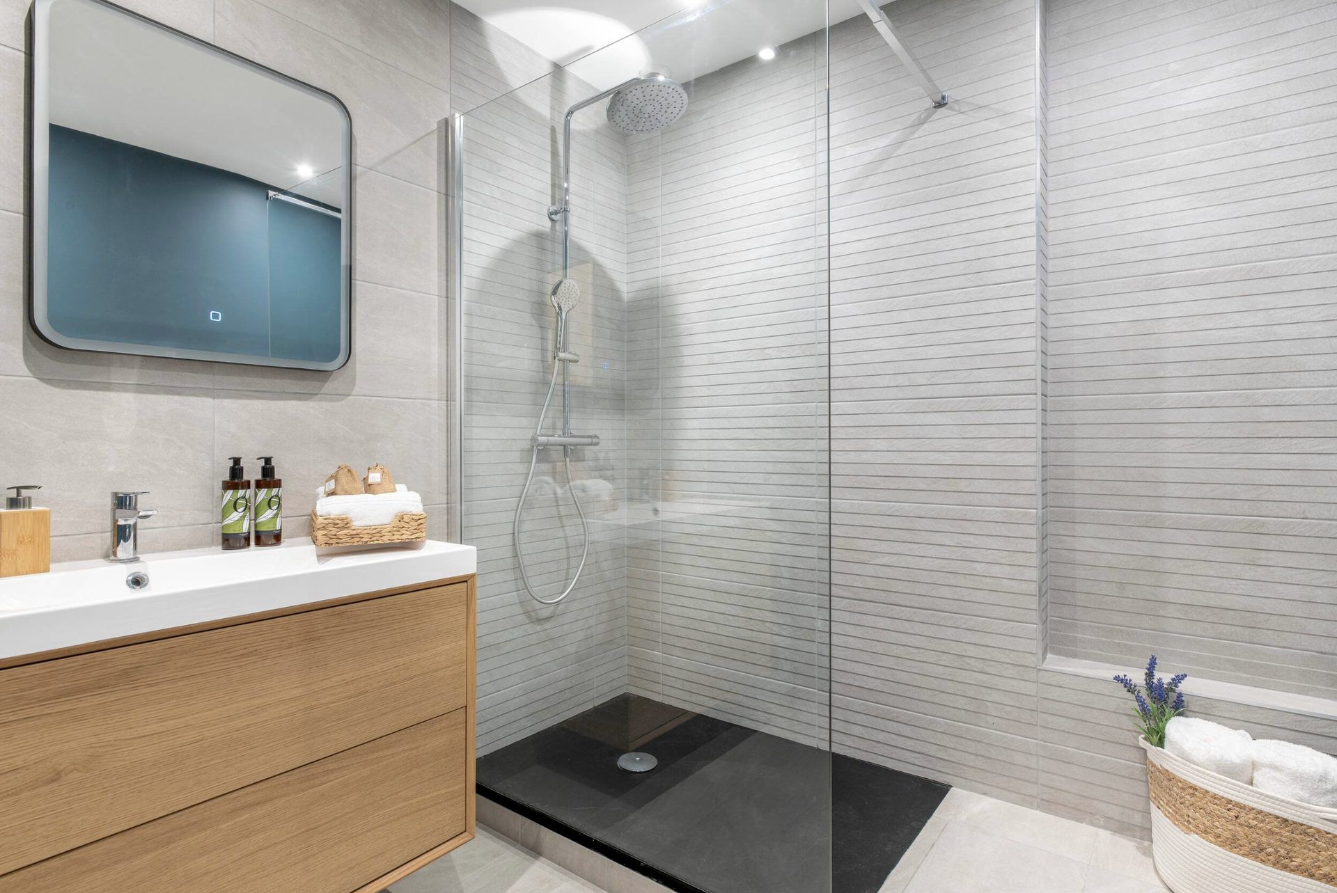 Bathroom at Gilli with a walk-in rainfall shower, wooden vanity, and backlit mirror