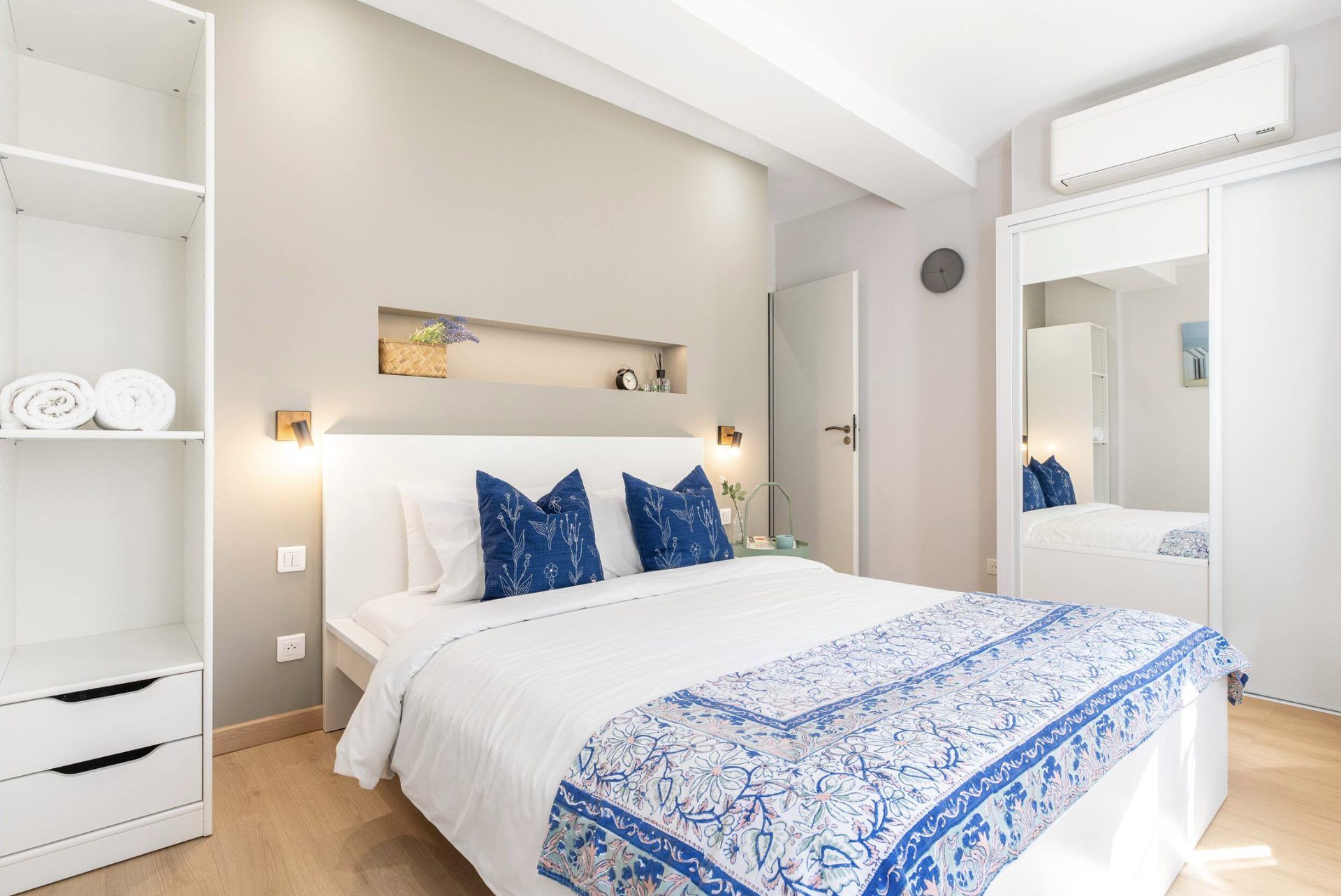 Main bedroom at Gilli — king-size bed with blue cushions, mirrored wardrobe, and air conditioning