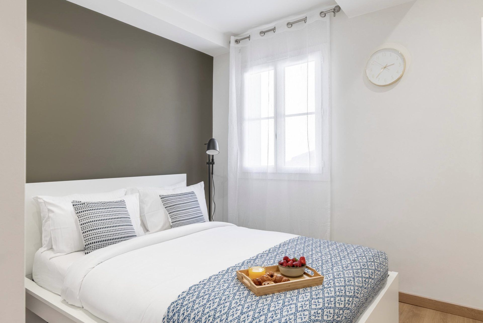 Second bedroom at Gilli with a double bed, olive-grey accent wall, and sheer curtains