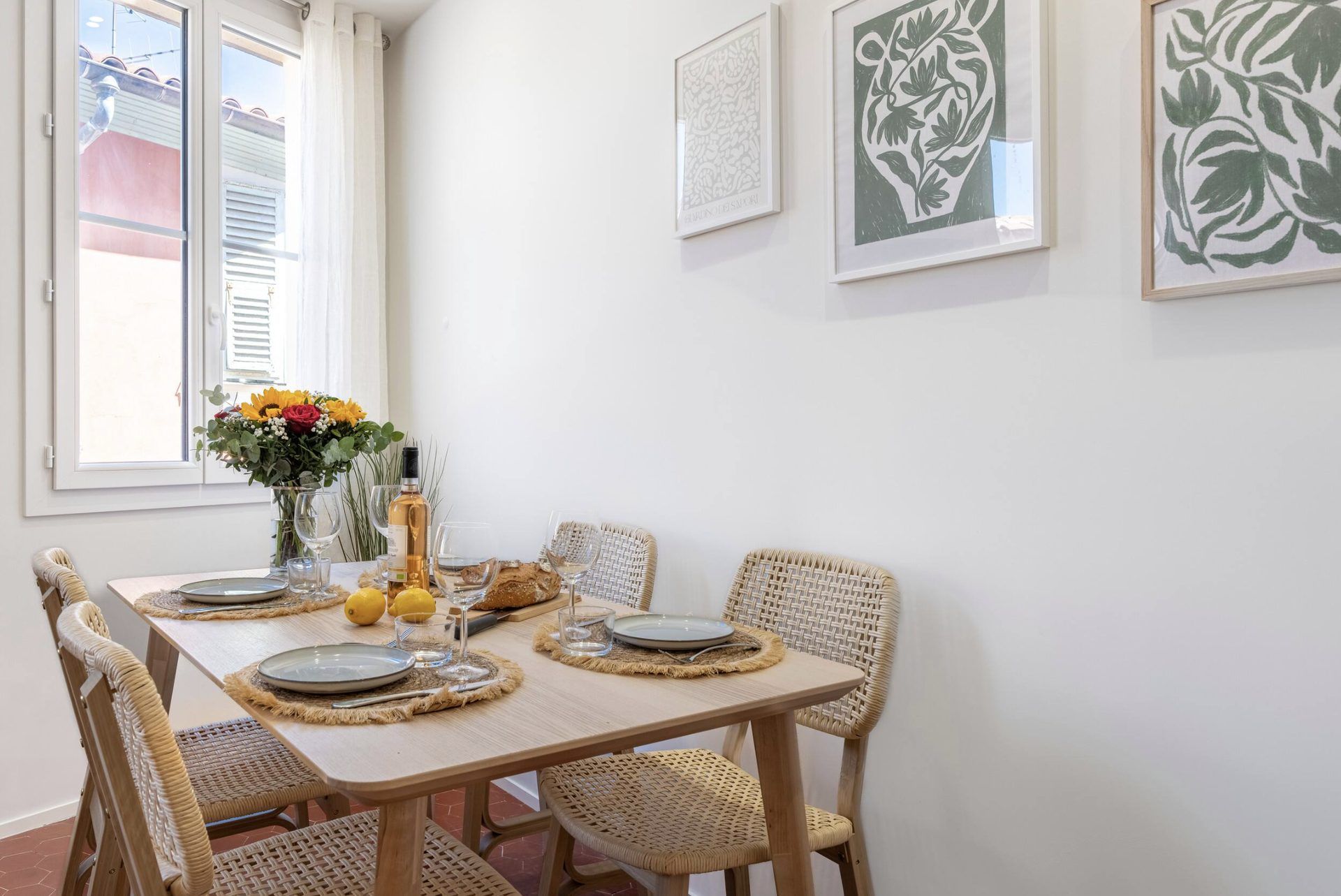 Dining table at Gilli set for four, with rattan chairs and botanical prints